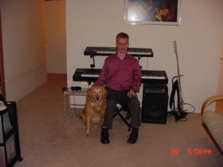 Photo of ivan and Seeing Eye dog Zeke, with two
keyboards and a bass in the background.